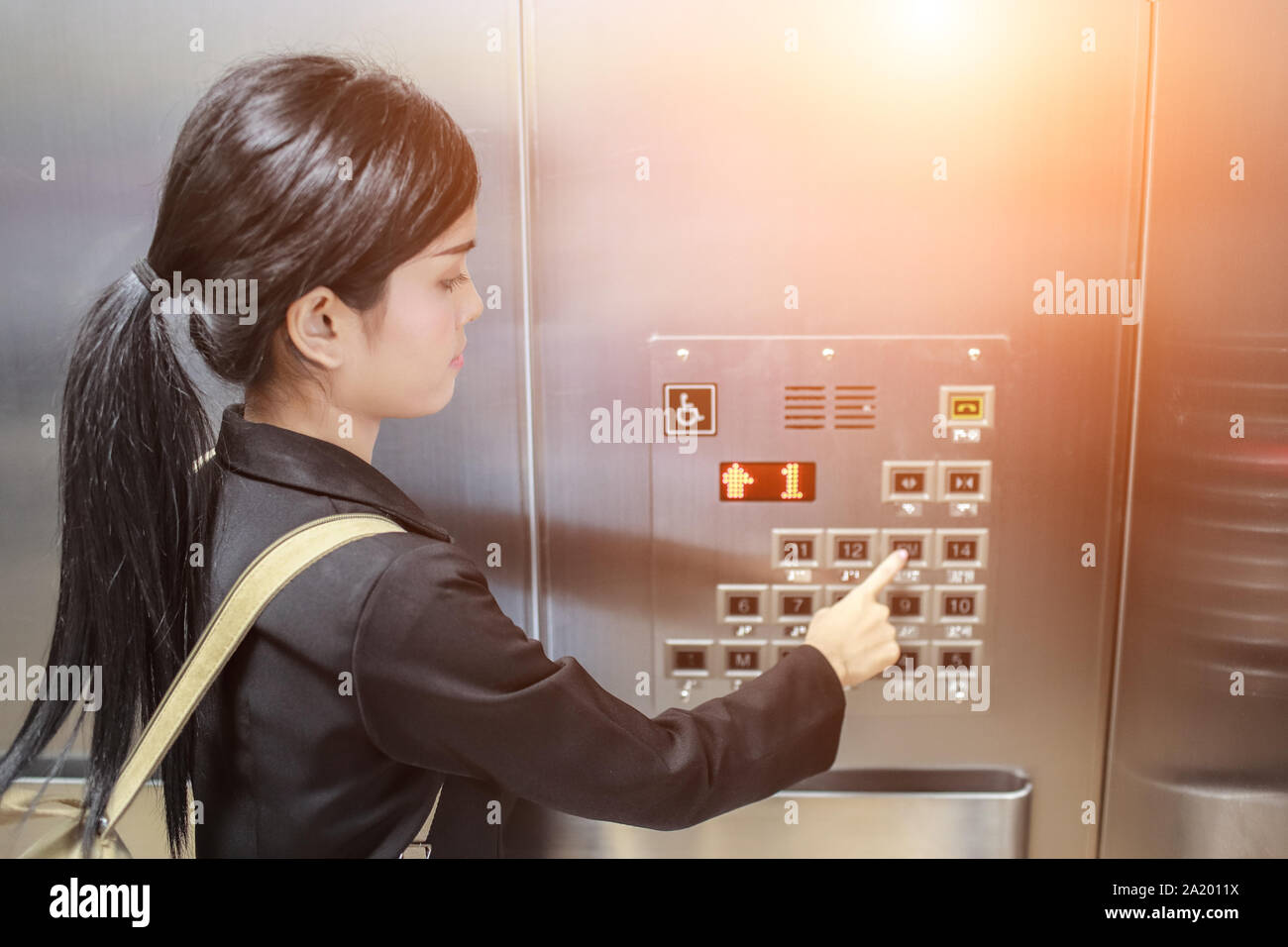 businesswomen pressing elevator button with sun light effect Stock