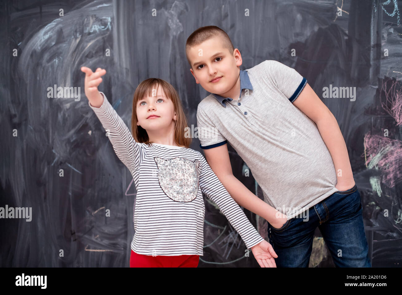 group portrait of happy childrens boy and little girl standing in front of black chalkboard Stock Photo