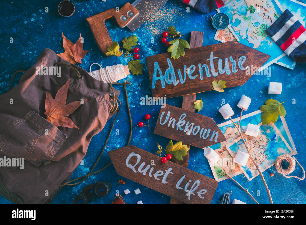 Road sign with Adventure, Unknown and Quiet Life directions. Travel essentials creative header with socks, maps, and marshmallows, wanderlust concept Stock Photo