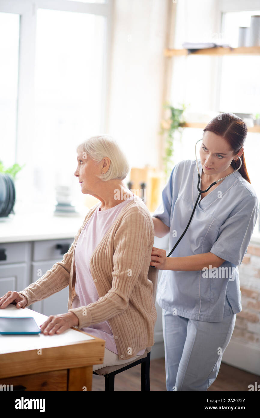 Nurse examining retired lady feeling sick and tired Stock Photo