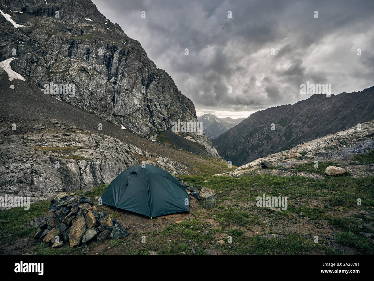 Green tent in the grey mountain valley with overcast rainy clouds in Karakol national park, Kyrgyzstan Stock Photo