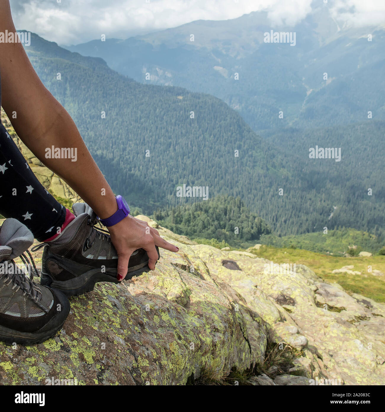The man in the mountains showing his hand to unstick sole from hiking boots Stock Photo