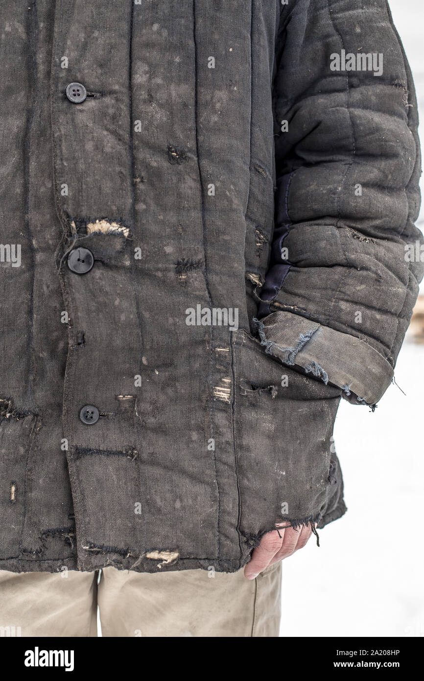 Man Dressed In Shabby Old Worn Working Clothes With Patches, And Put