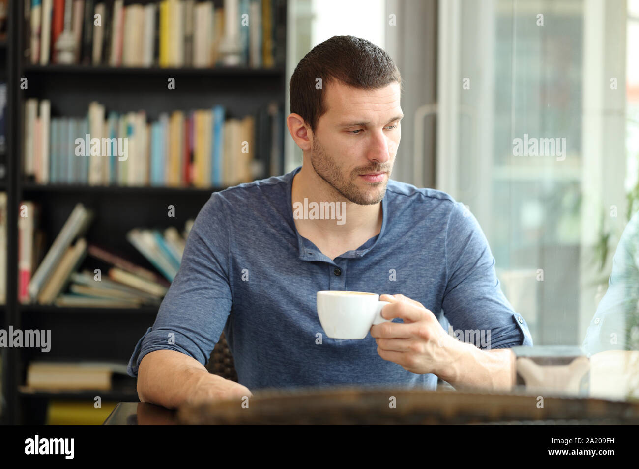 Pensive sad man looks away through a window in a coffee shop or home Stock Photo