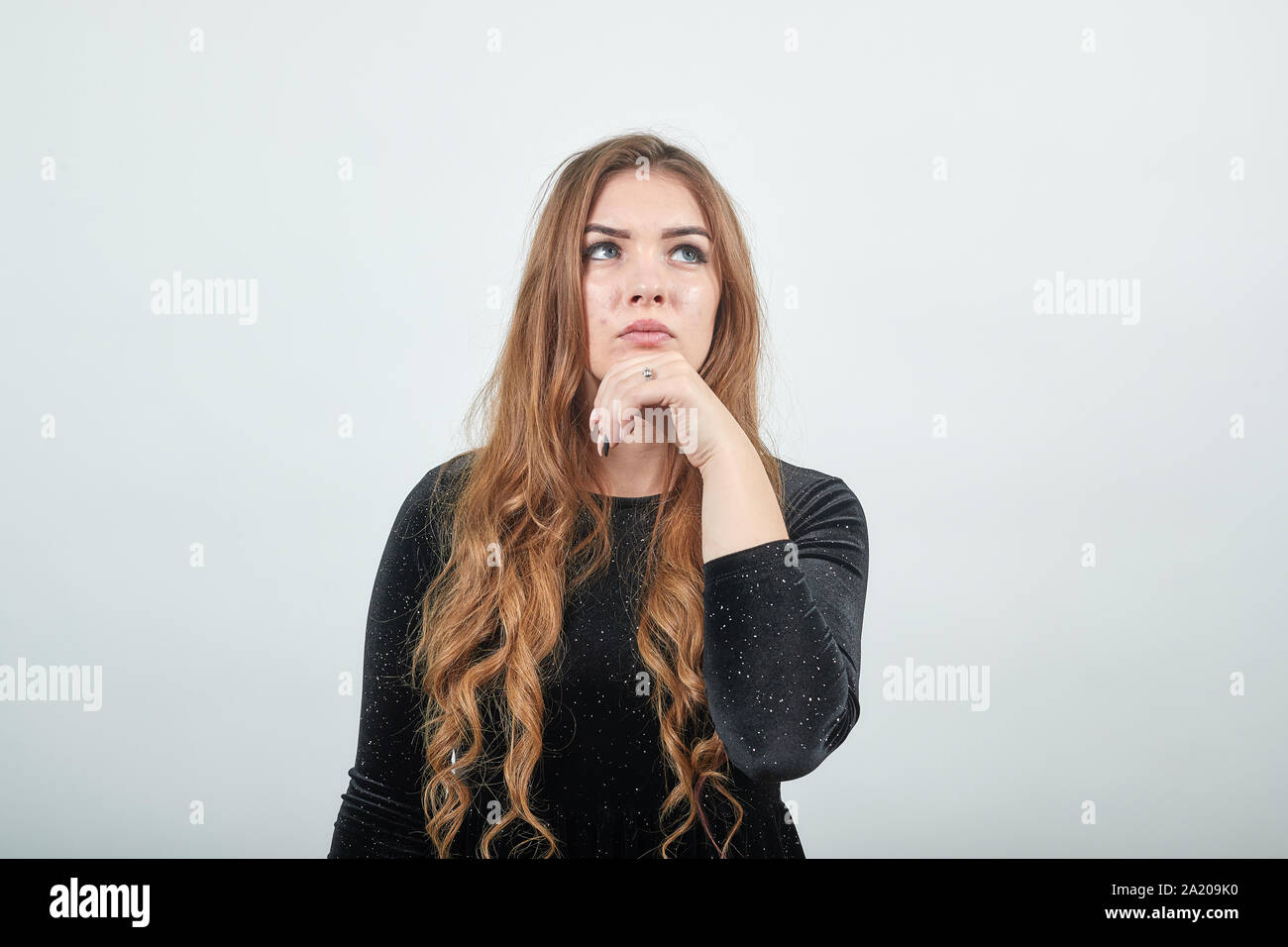 girl brown haired in black dress over isolated white background shows emotions Stock Photo