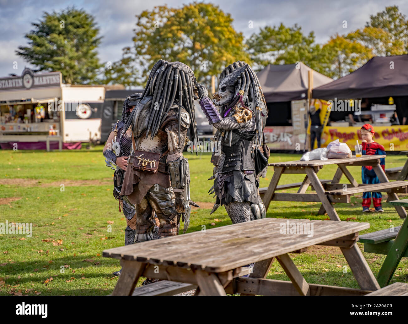 Small group of people in fancy dress as characters from the Sci-fi movie, Predator, getting ready to entertain the crowd queuing for Nor-Con Stock Photo