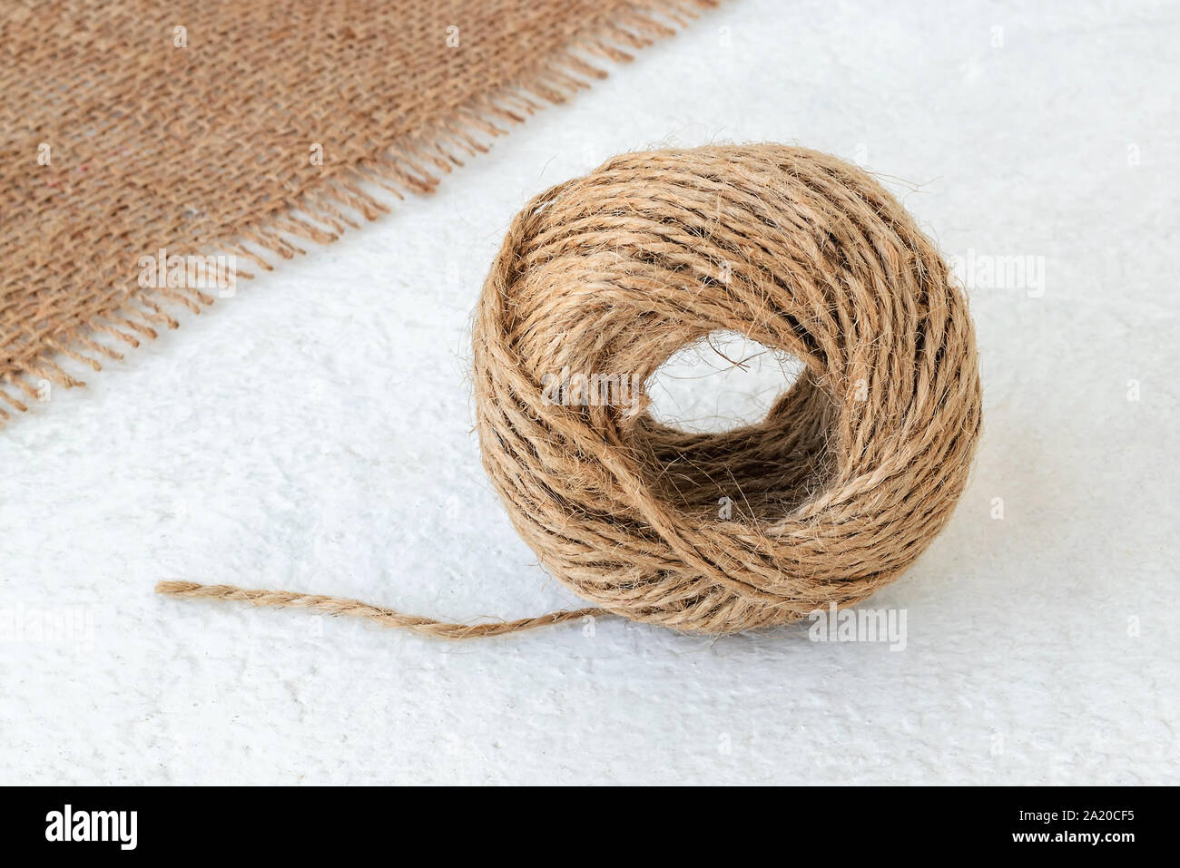 Natural hemp cord ball and burlap on a rough white surface. Roll of