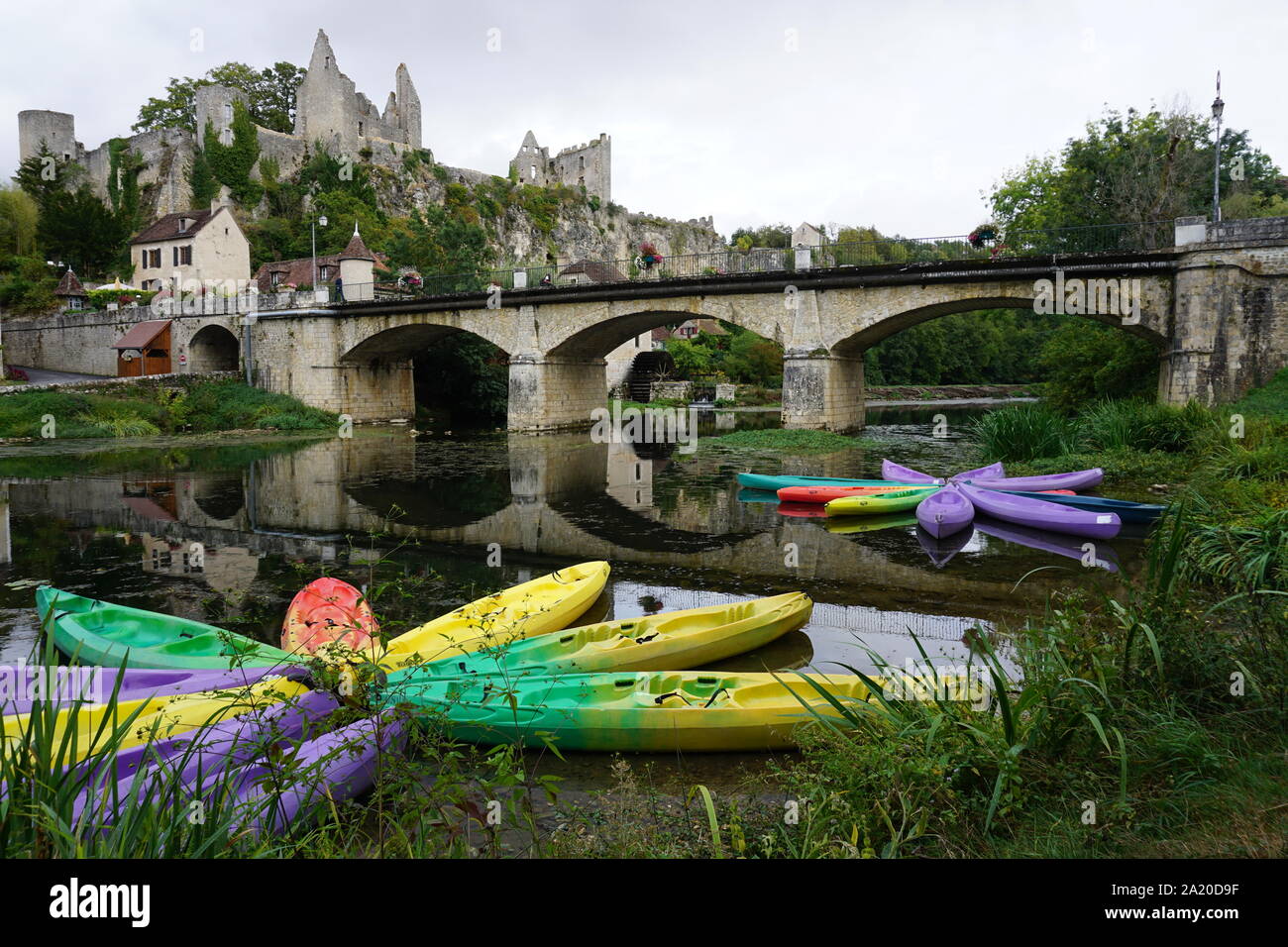 colorful canoes moored as flowers in a small village in France with an old stone fortress and bridge Stock Photo