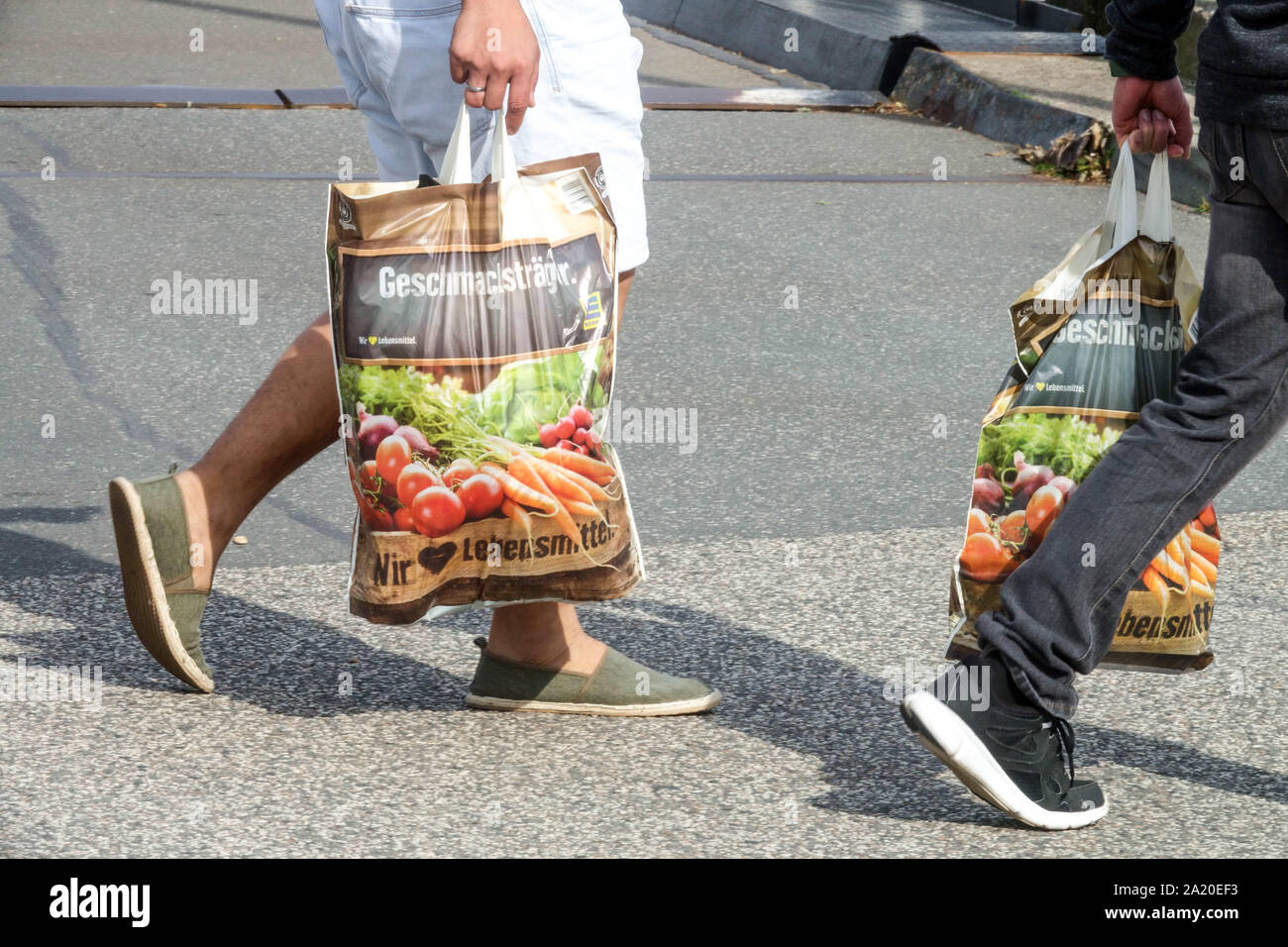 Customers take away their shopping in full plastic bags from the supermarket Germany Europe Stock Photo