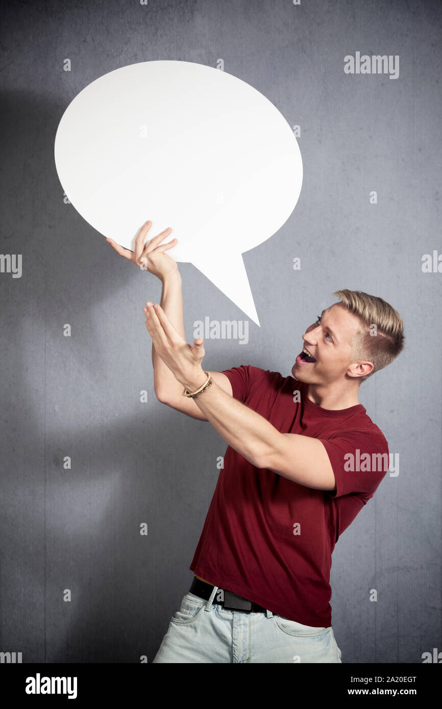 Joyful man presenting white empty speech balloon. Stock Photo
