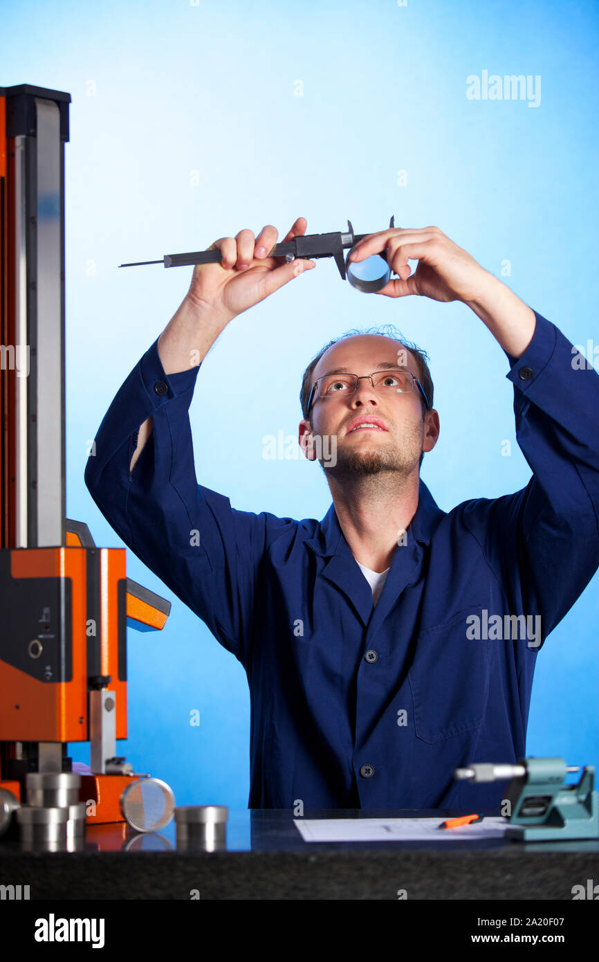 Engineer measuring with caliper against light Stock Photo