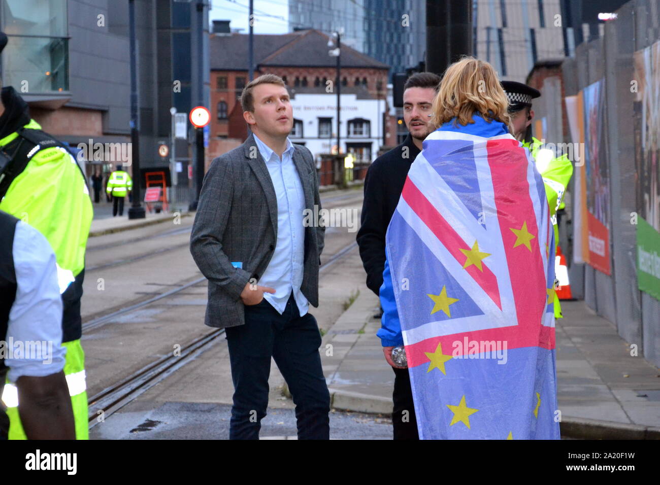 An altercation took place near the main gate of the Conservative Party Conference, 2019, in Manchester, uk.  A member of the Stand of Defiance European Movement, wearing a union jack flag, talks to police after EU flags belonging to the group were allegedly stolen and damaged. Femi Oluwole of the anti-Brexit Our Future Our Choice group helped the owner of the flags and posted video of the incident on his twitter feed. The media reports that one of the men who took the flags is a Conservative Councillor. Stock Photo