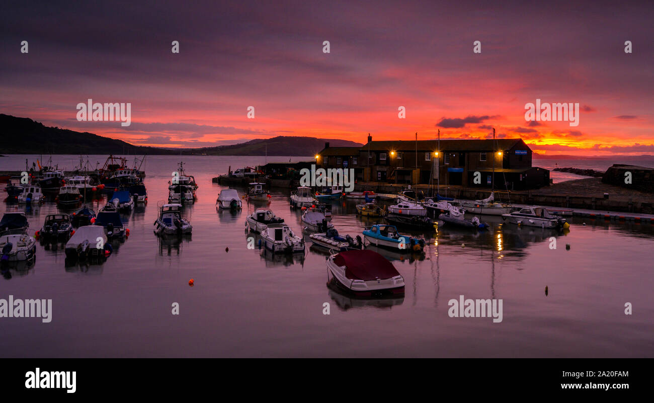 Lyme Regis, Dorset, UK. 30th September 2019. UK Weather: Red sky in the morning shepherd's warning....The sky over the historic Cobb Harbour at Lyme Regis glows with vibrant red colour at sunrise. Credit: Celia McMahon/Alamy Live News. Stock Photo