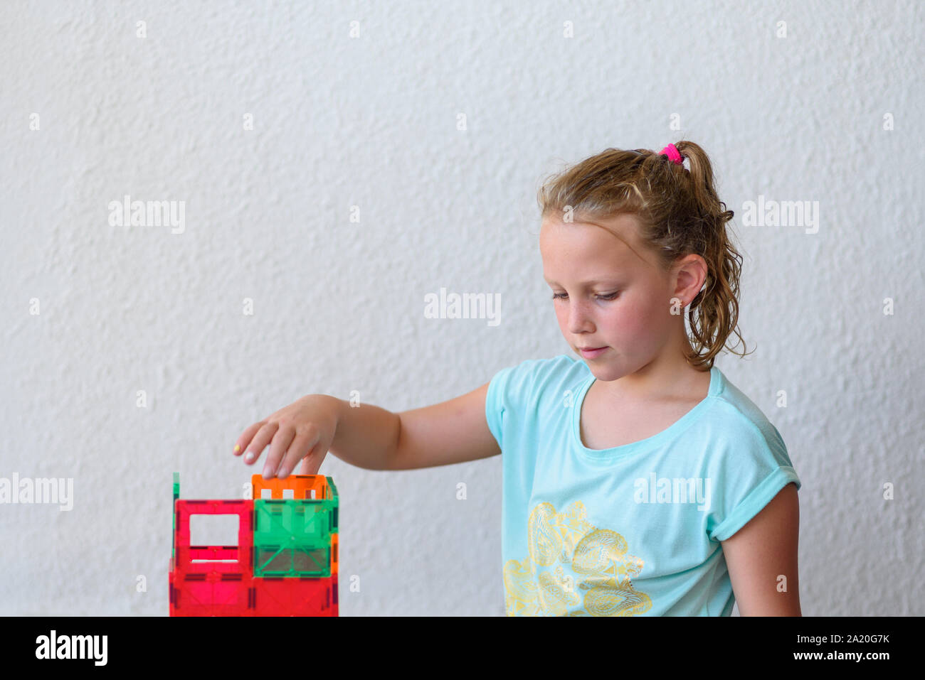 Beautiful teenage girl playing with lots of colorful plastic blocks ...