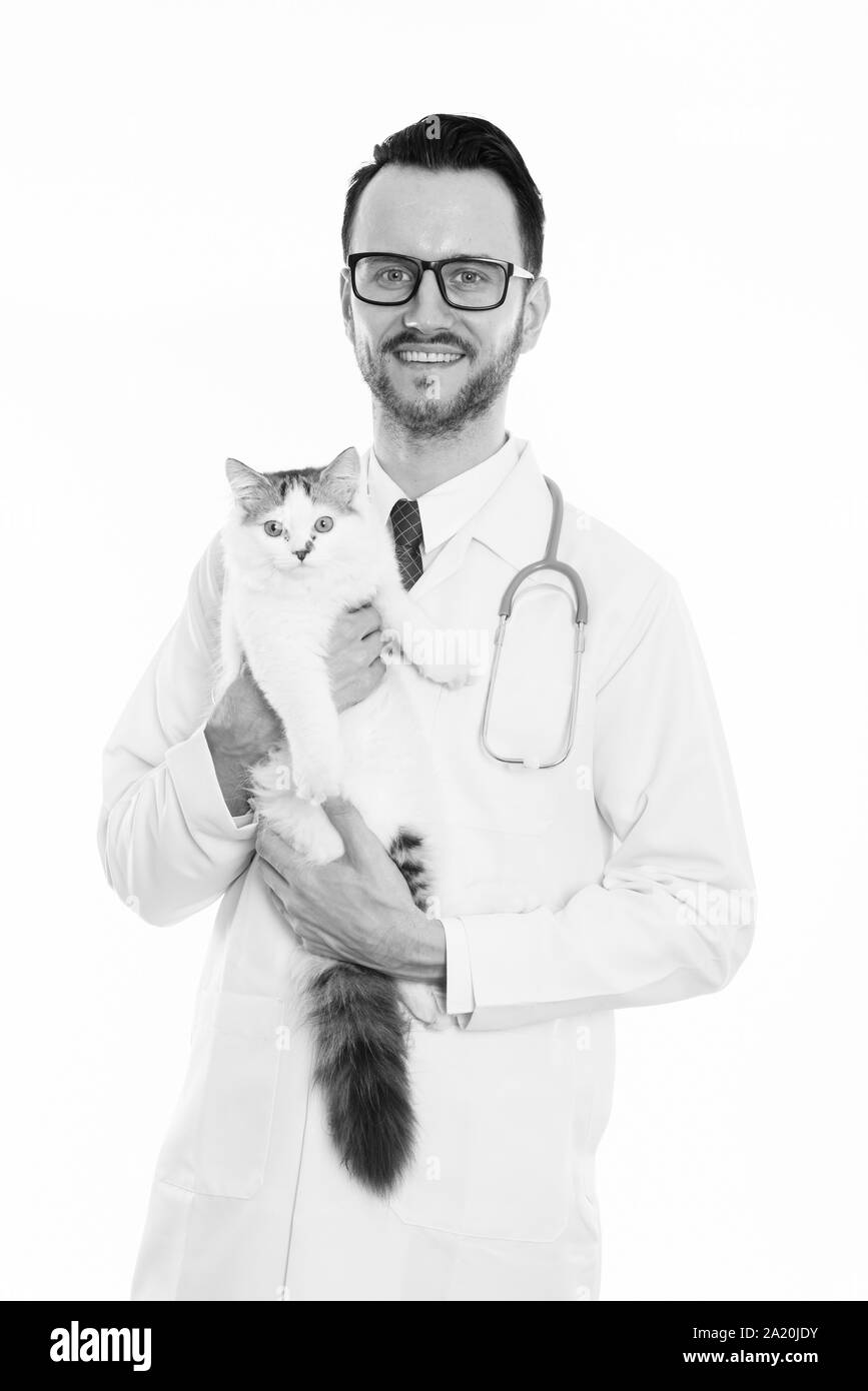 Studio shot of happy young man doctor smiling while holding cute cat Stock Photo