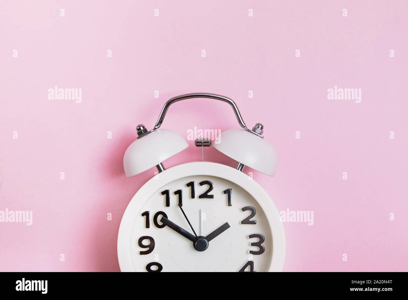 Retro analog alarm clock on pastel pink background Stock Photo