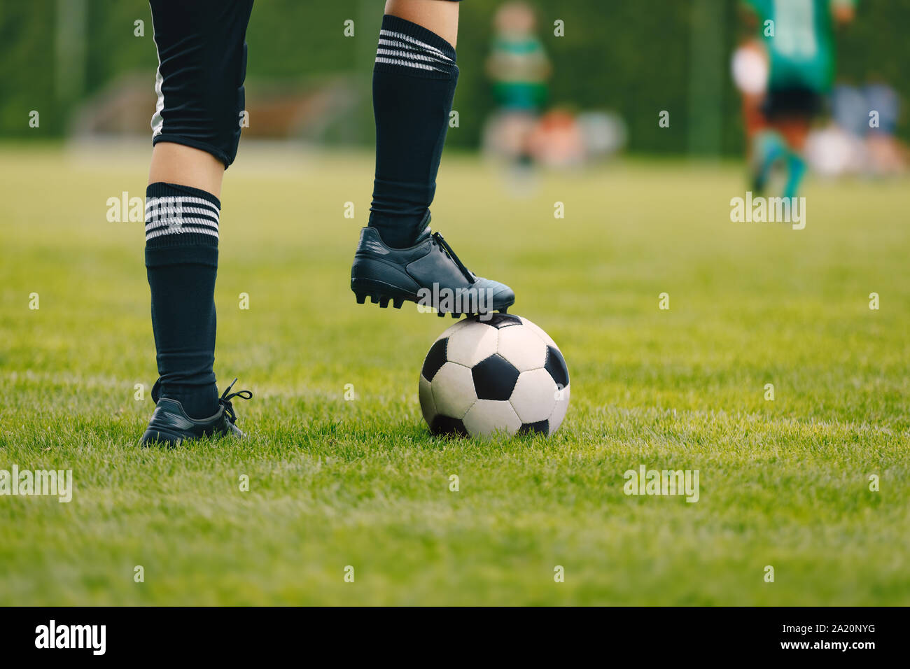 One young football player with ball on grass field. Boy in a sportswear. Player wearing black football socks and soccer cleats. Football horizontal cl Stock Photo