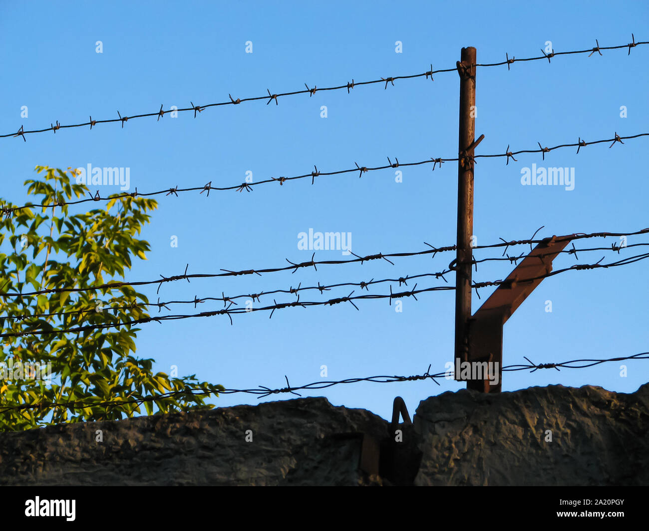 Two threads of monobasic barbed wire and several lines of dibasic barbed wire, covered with rust, stretched on old metal brackets Stock Photo