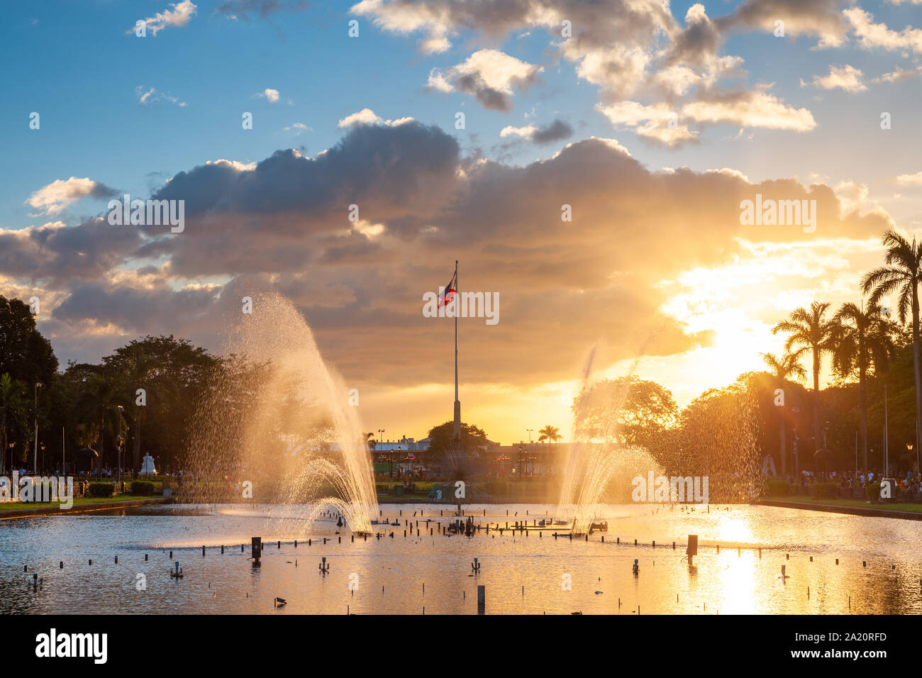View of a fountain in Rizal Park with a flag of the Philippines under beautiful sunset light, Manila, Philippines. Stock Photo
