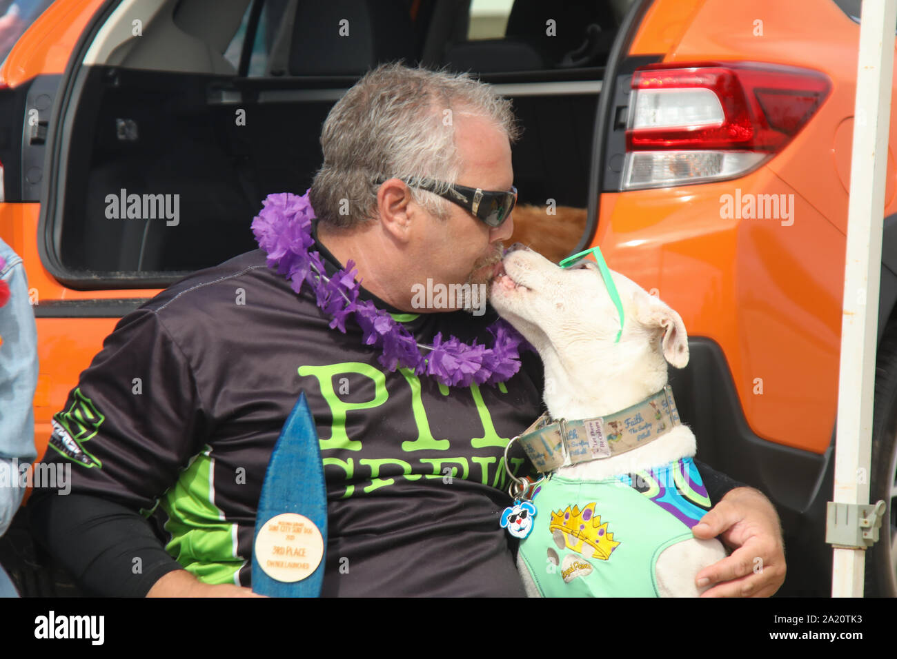 Huntington Beach, California, USA. 28th September, 2019. James Wall gets a 'kiss' from his dog Faith, an American Pitbull Terrier, as they are awarded 3rd Place in the Owner-Launched Division at the 11th Annual Surf City Surf Dog Competition held at Huntington Dog Beach in Huntington Beach, California on September 28, 2019. Stock Photo