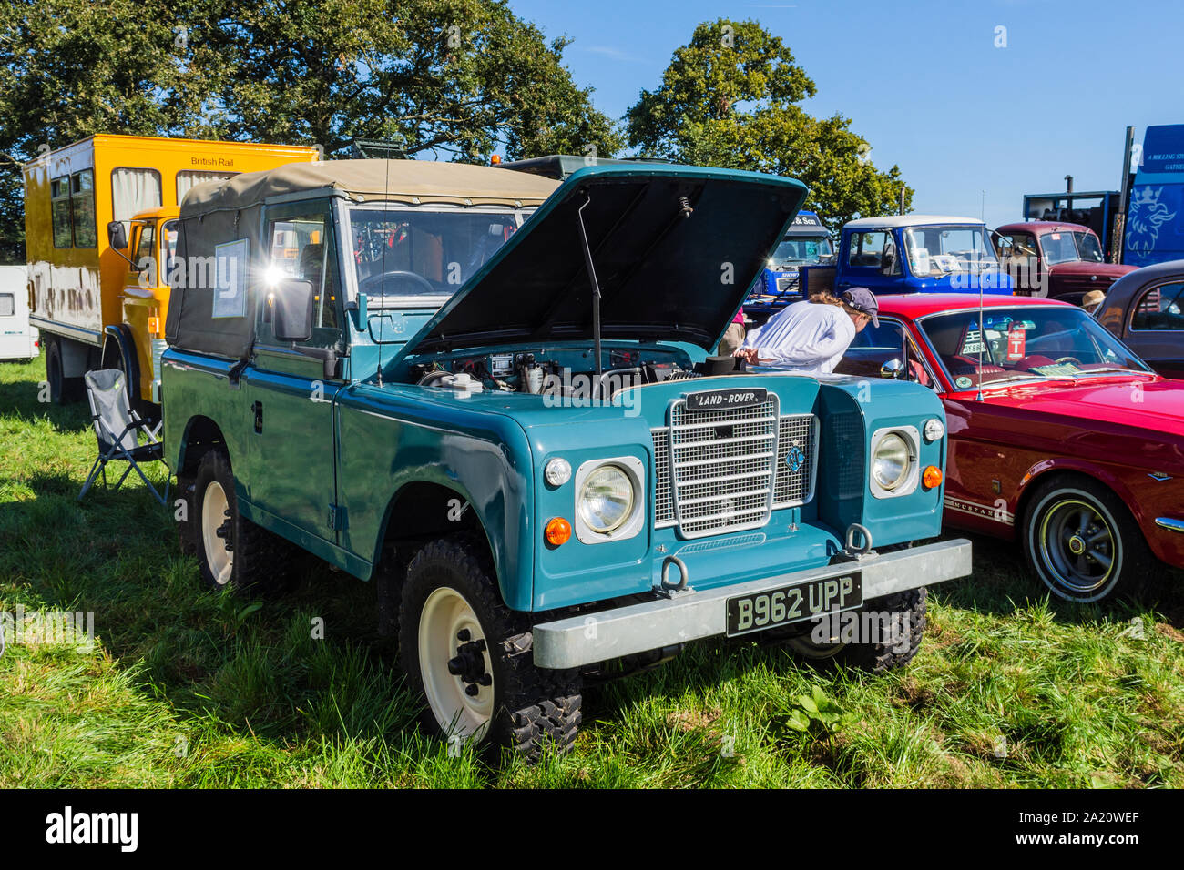 A classic Landrover Defender with its bonnet open seen from the