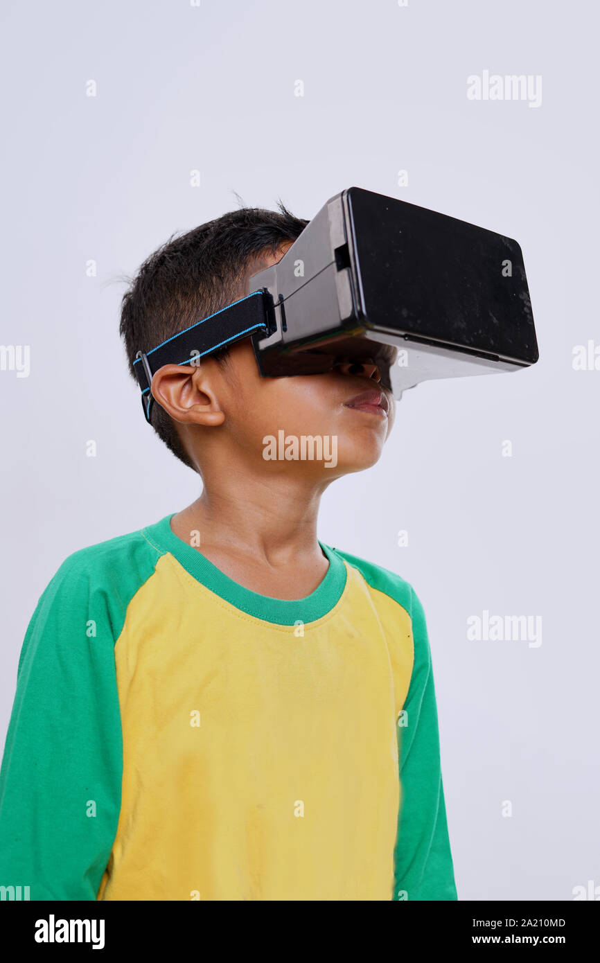 Schoolboy standing using virtual reality glasses on white background Stock Photo