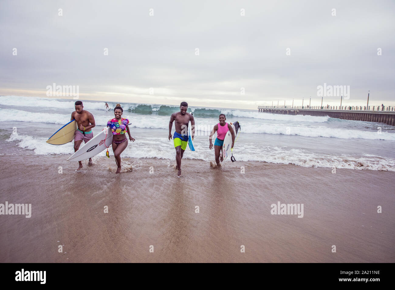 People walking with surfboards along Durban beach Stock Photo Alamy