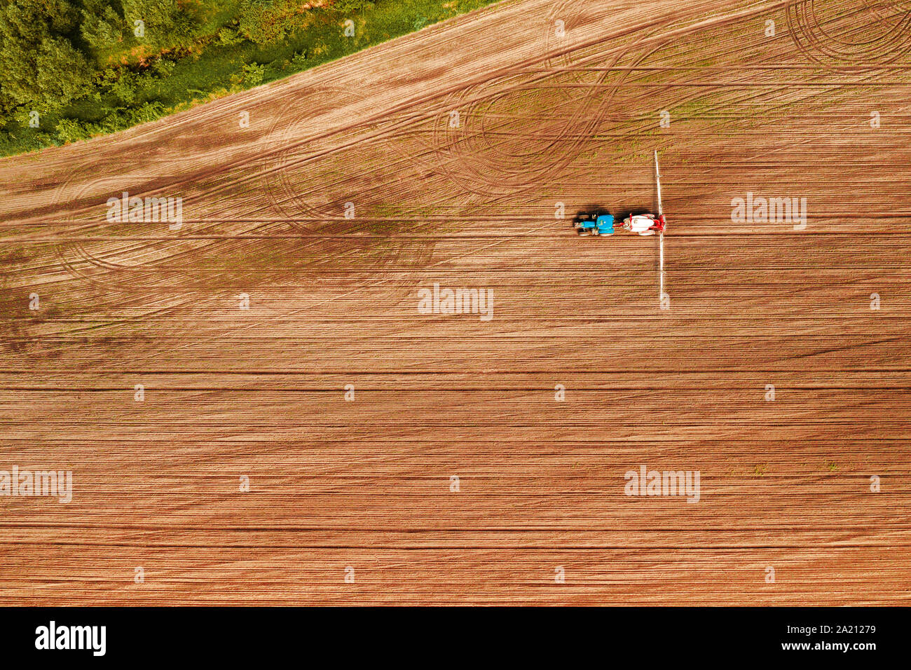 Tractor spraying crops in field, aerial view from drone pov Stock Photo