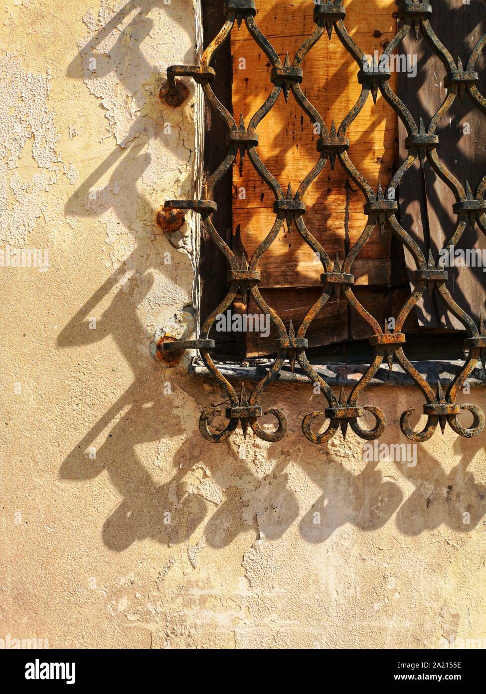 old barred window casting shadow on the wall Stock Photo