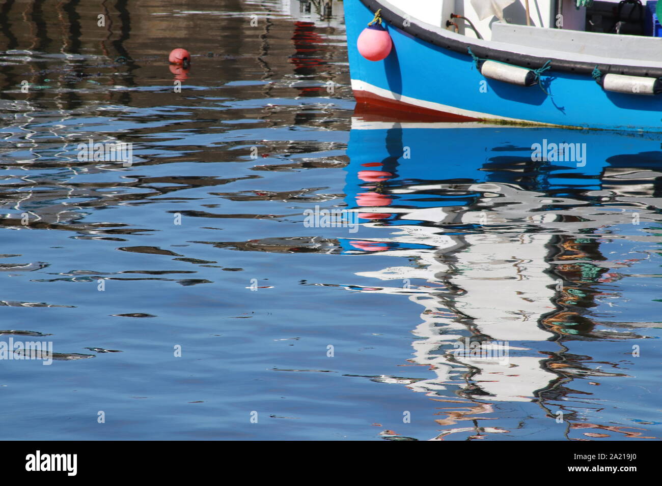 Fishing boats reflected in water of harbour Stock Photo - Alamy