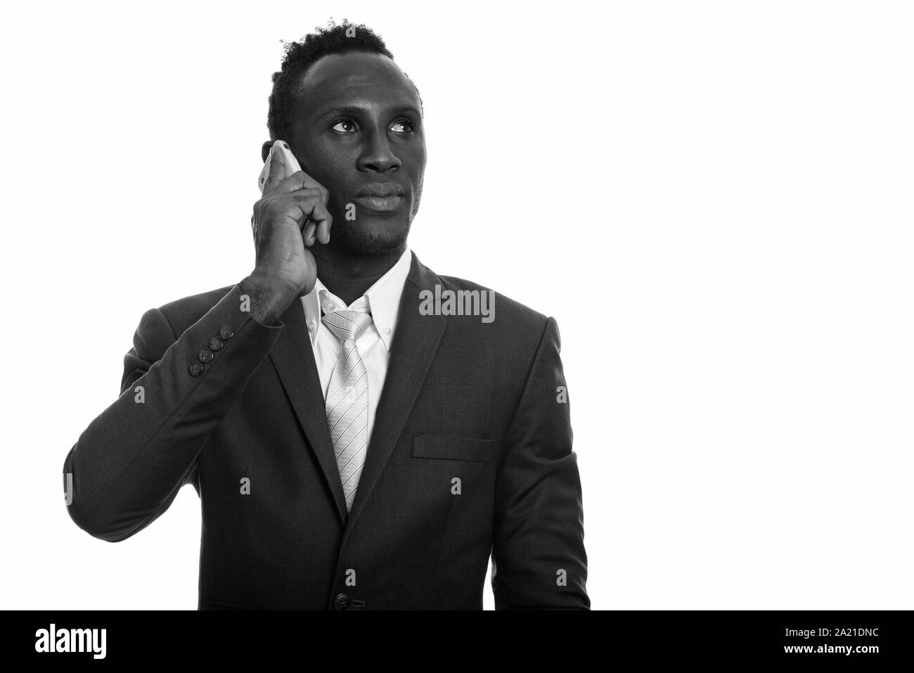 Young black African businessman talking on mobile phone while thinking Stock Photo