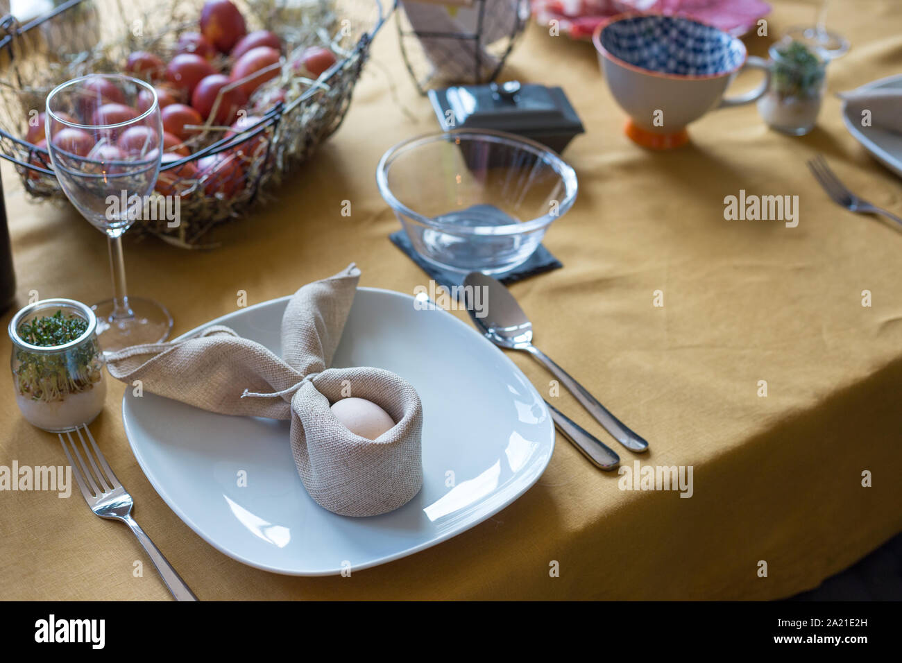 Real family table set for Easter breakfast in traditional Polish home. Basket filled with eggs colored with onion skins. Stock Photo
