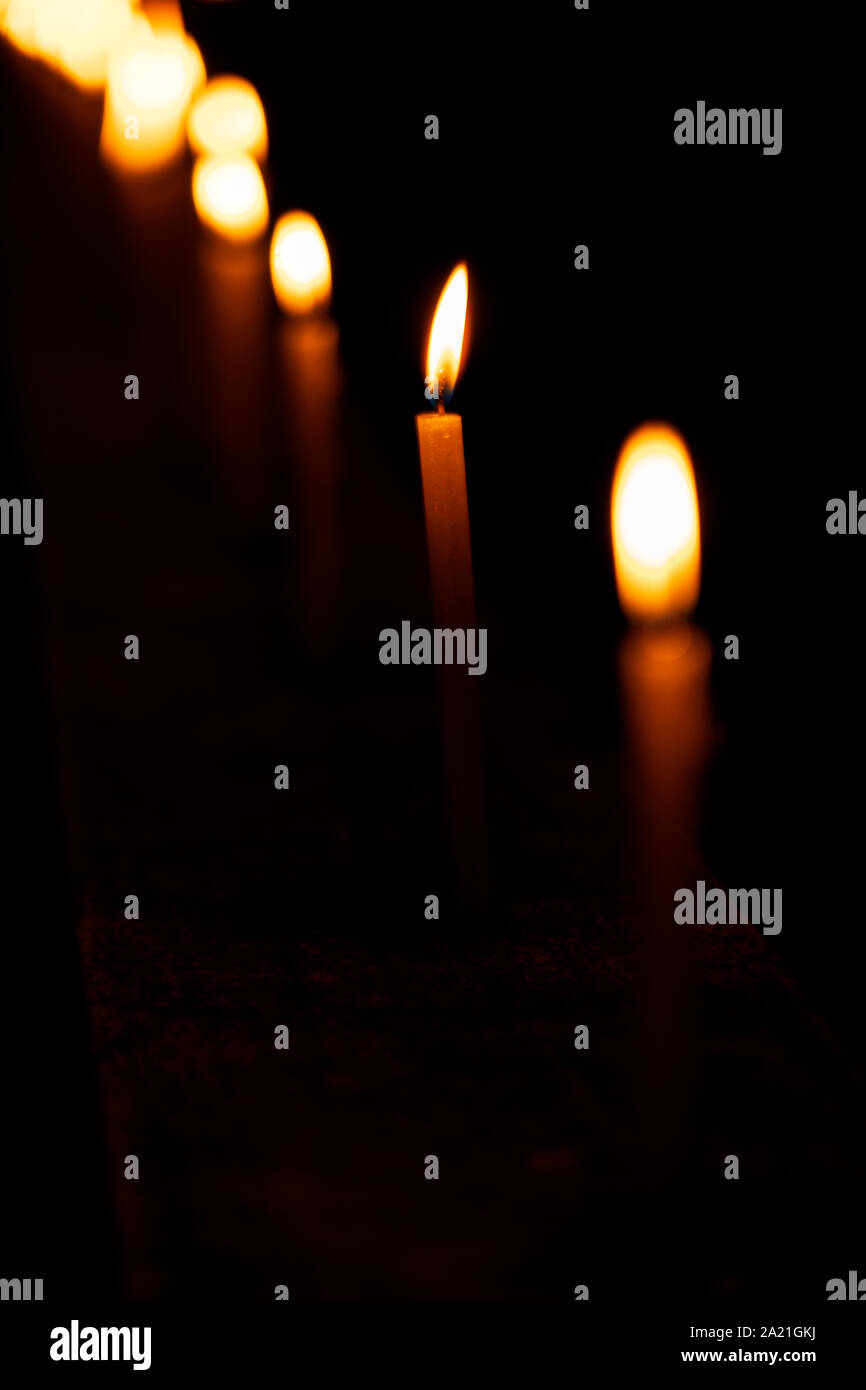 Beautiful candles burning in a row or line pattern at a temple or church during Diwali celebration or ceremony at night. Background stock photo of fes Stock Photo