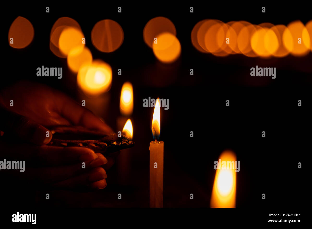 Indian housewife, female hand lighting up the candle with a diya or clay lamp or terracotta lamp. Background stock photo for diwali and other various Stock Photo