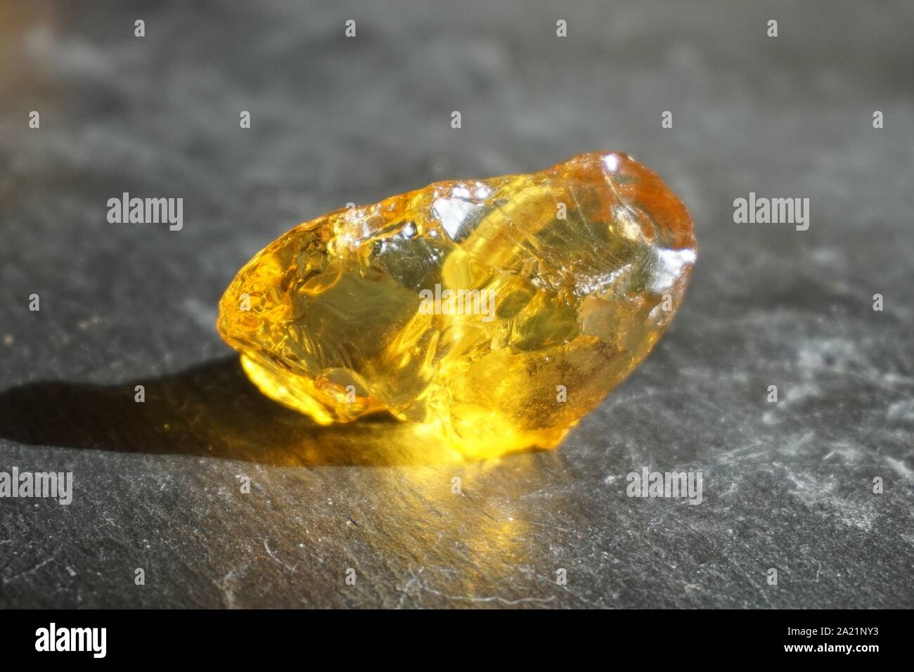 Piece of amber on gray slate background, lit by the sun Stock Photo