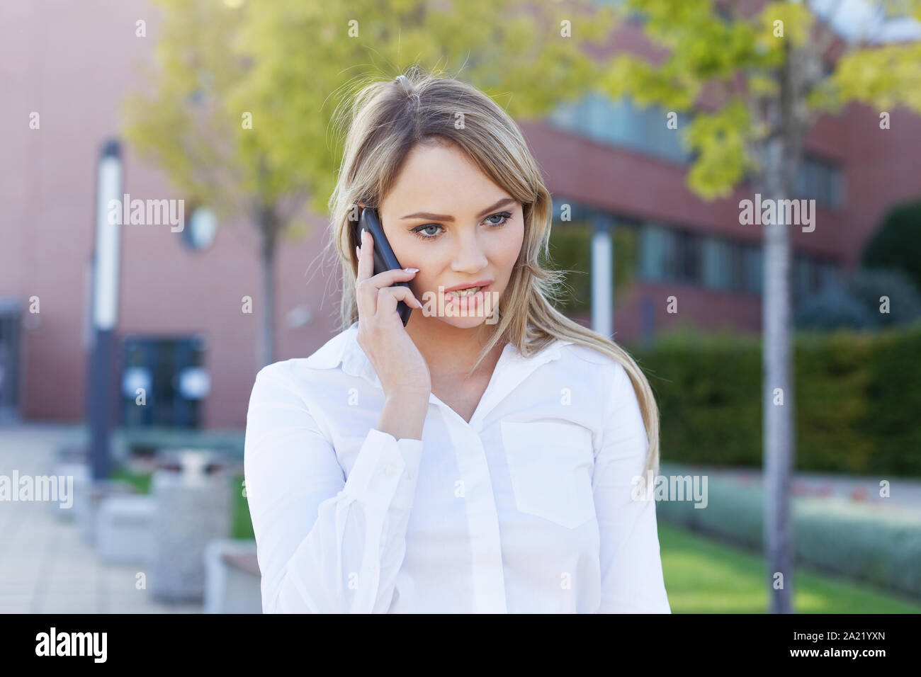 Serious blonde manager woman portrait calling in park Stock Photo
