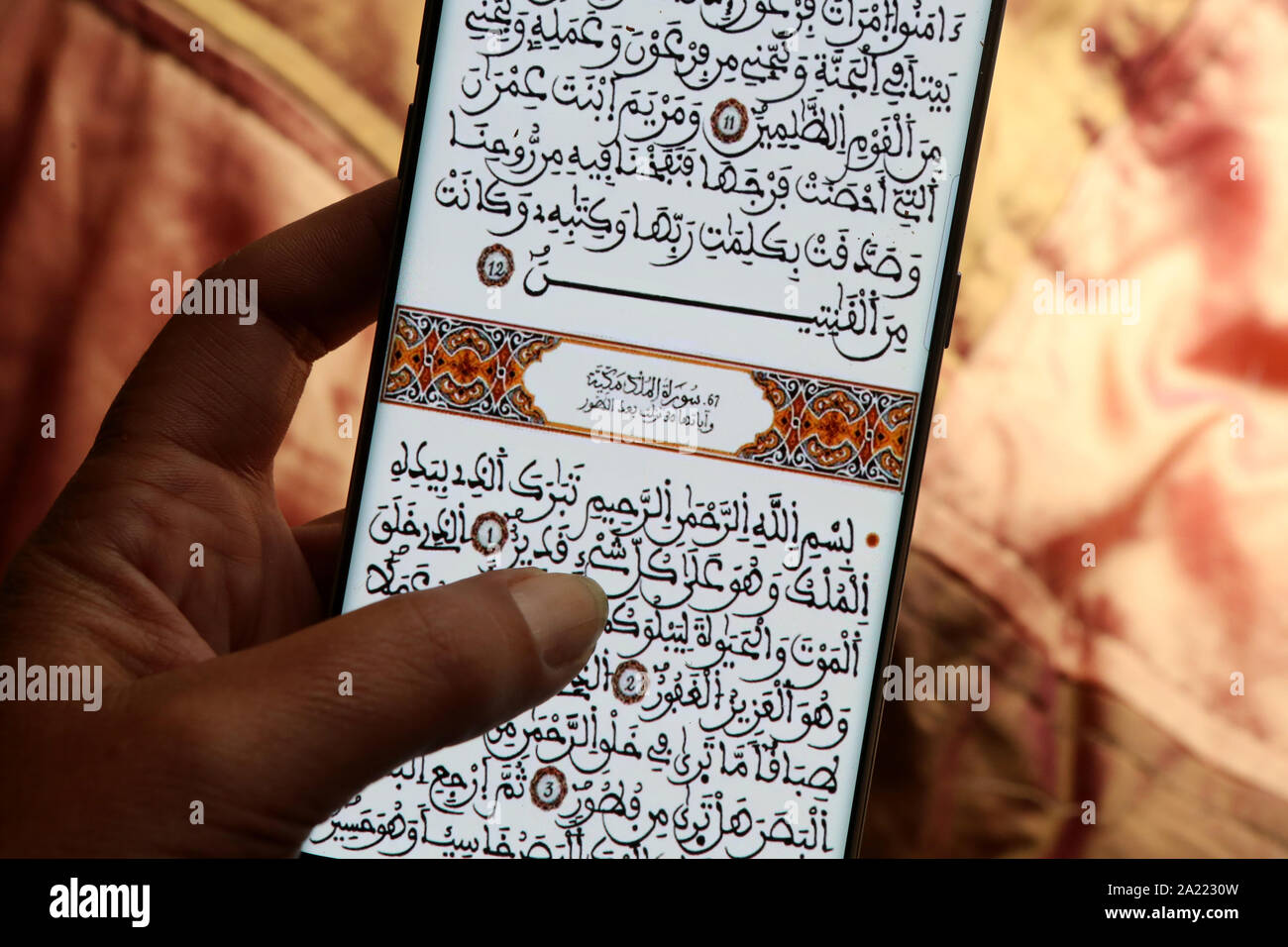 Jeune femme lisant le Coran sur son téléphone portable. Stock Photo