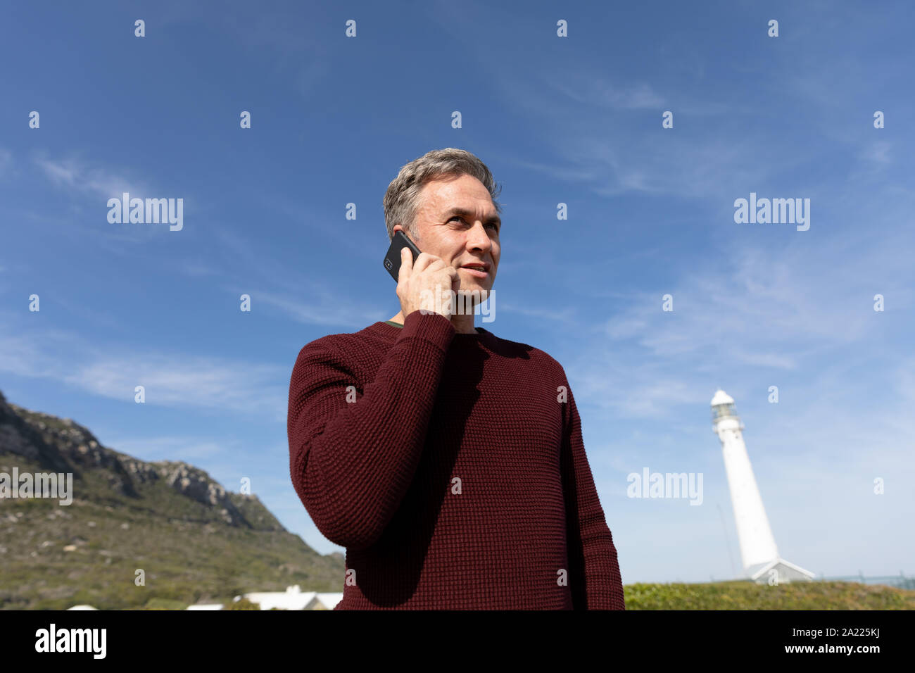 Man standing near lighthouse using smartphone Stock Photo