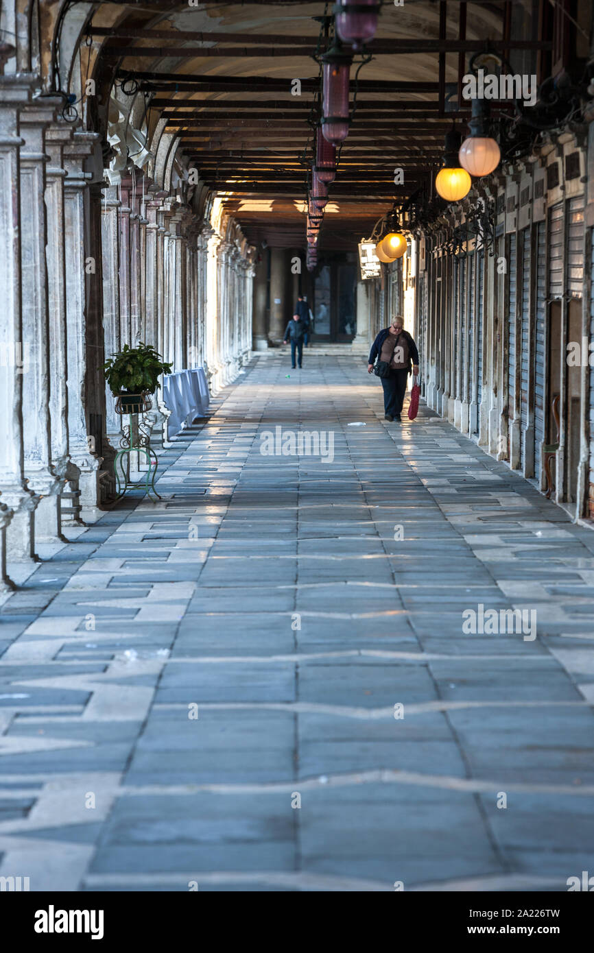 Woman walking with shopping bag down a Venice indoor market Stock Photo