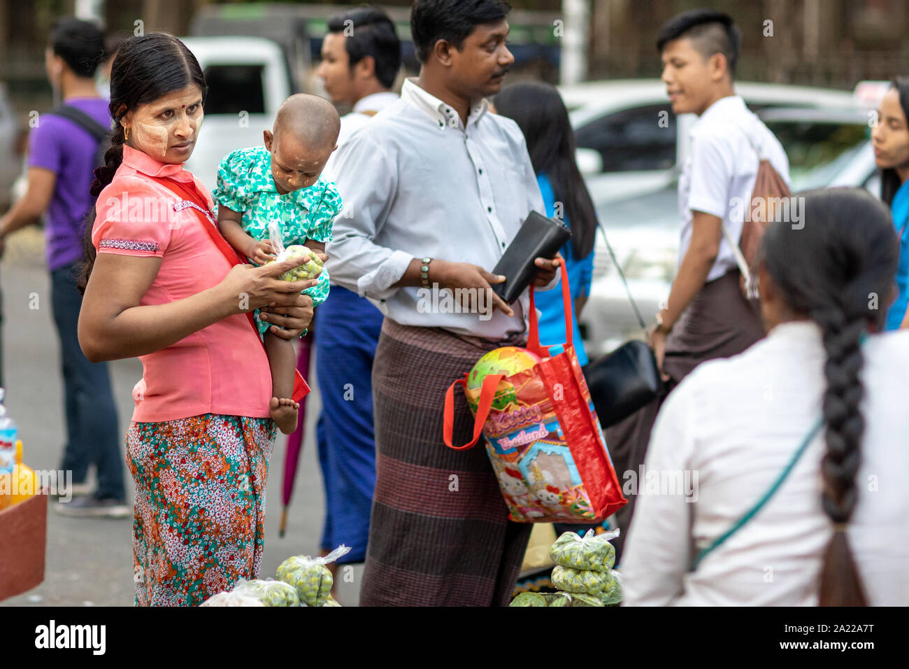 Mother with child buying food on the street in Yangon, Myanmar. Stock Photo