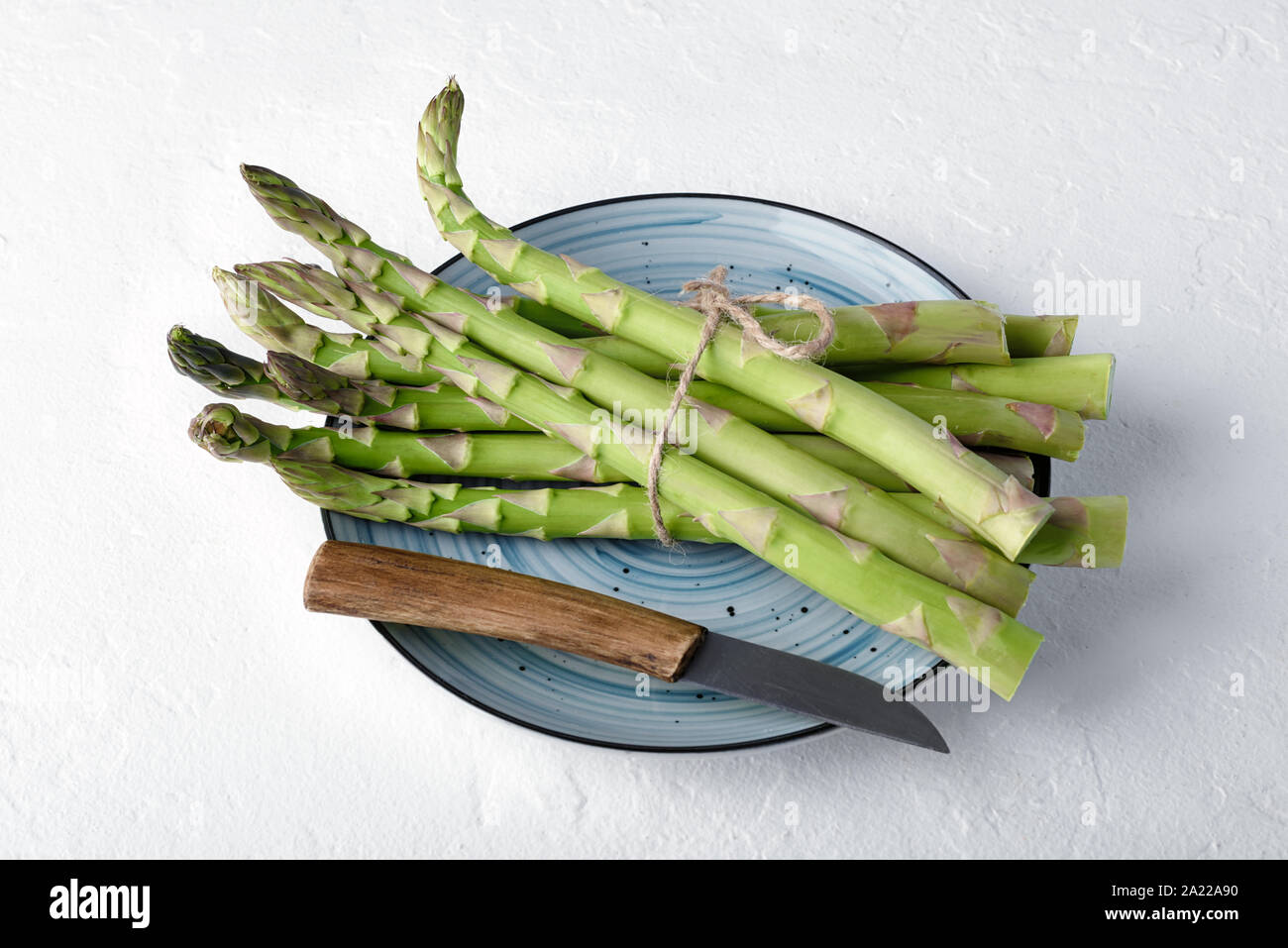 Green asparagus sprout on blue plate on white table. Food photography Stock Photo