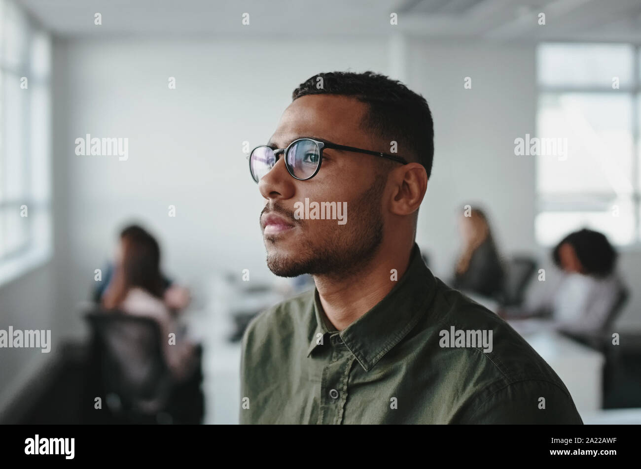 Close-up of a young african american business man entrepreneur wearing eyeglasses contemplating in office Stock Photo