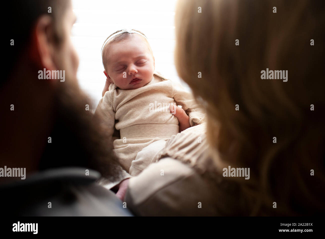 Downward view between mother and father of newborn baby girl sleeping