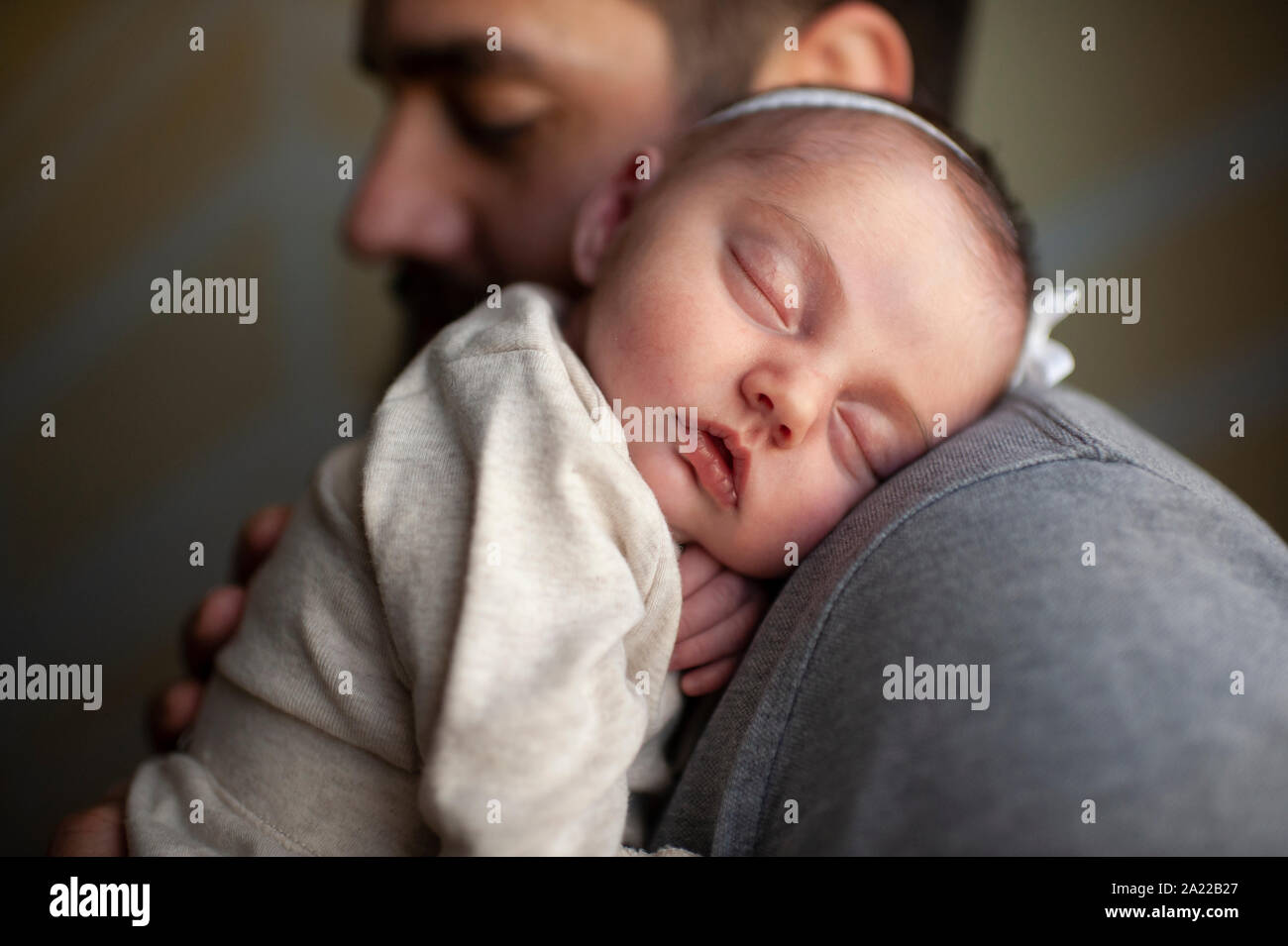 Close up of newborn baby's face sleeping on father's shoulder at home Stock Photo