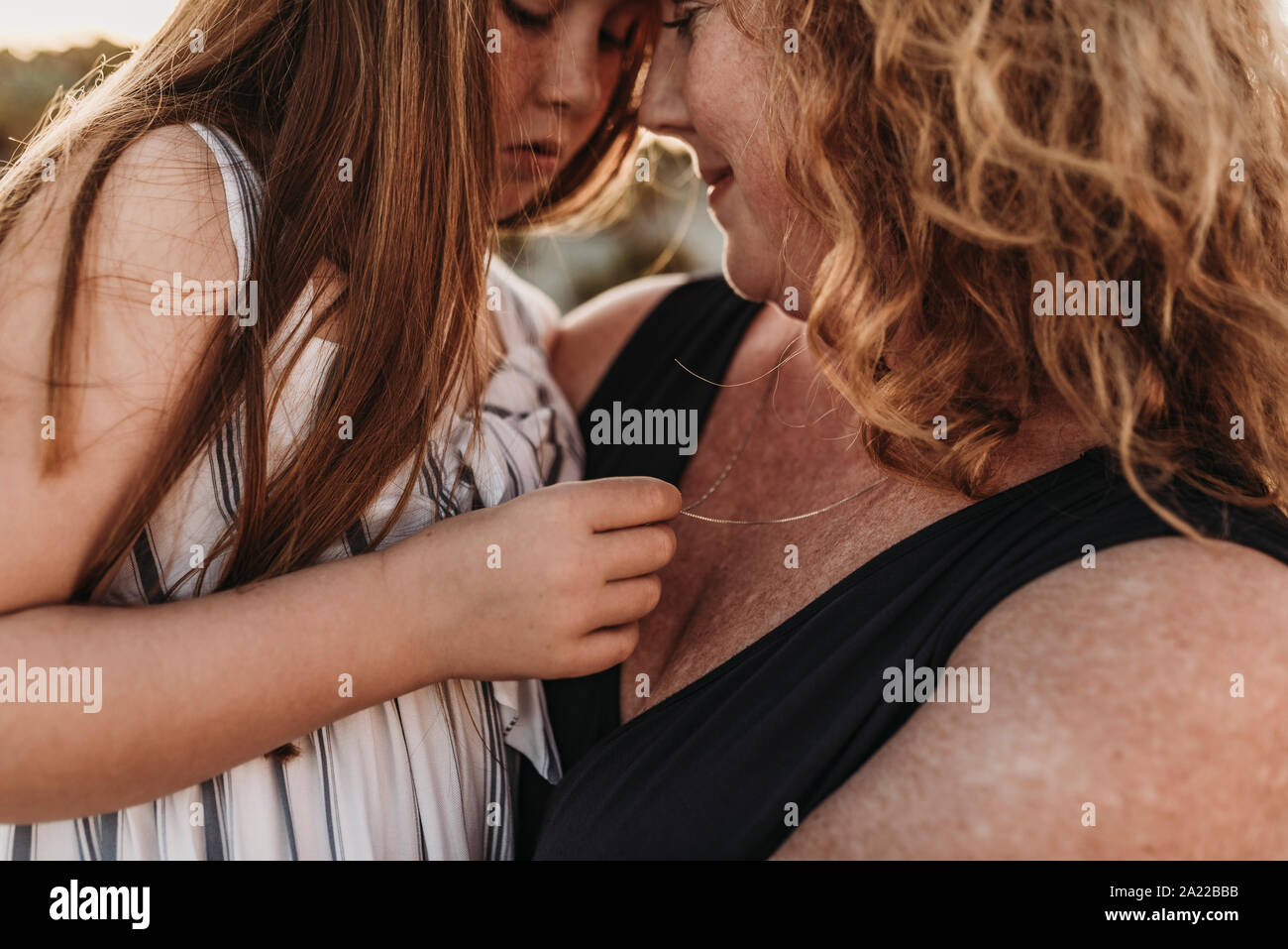 Side view of mother and redheaded elementary age daughter at sunset Stock Photo