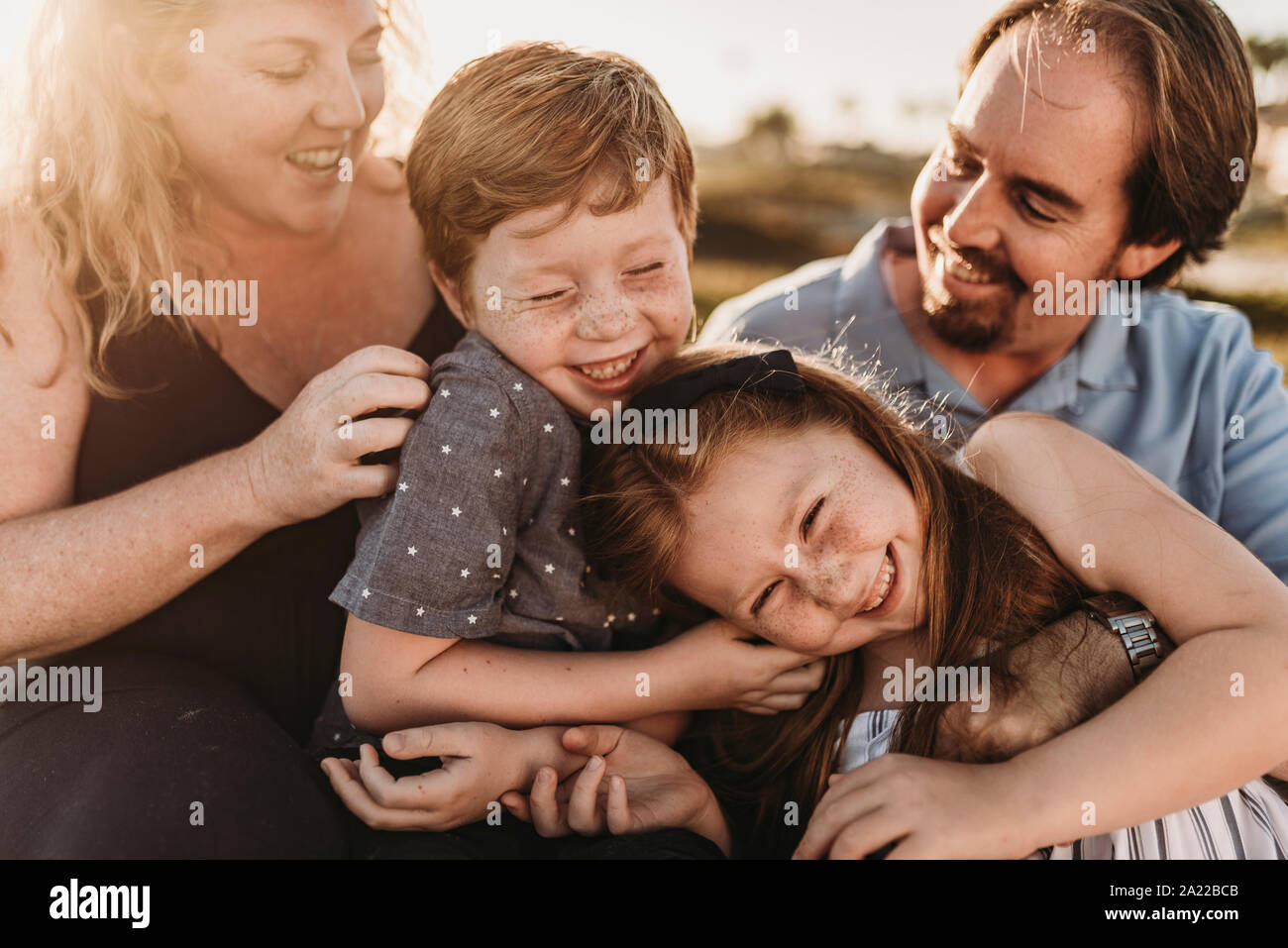 Close up detail of family of four playing during sunset at beach Stock Photo