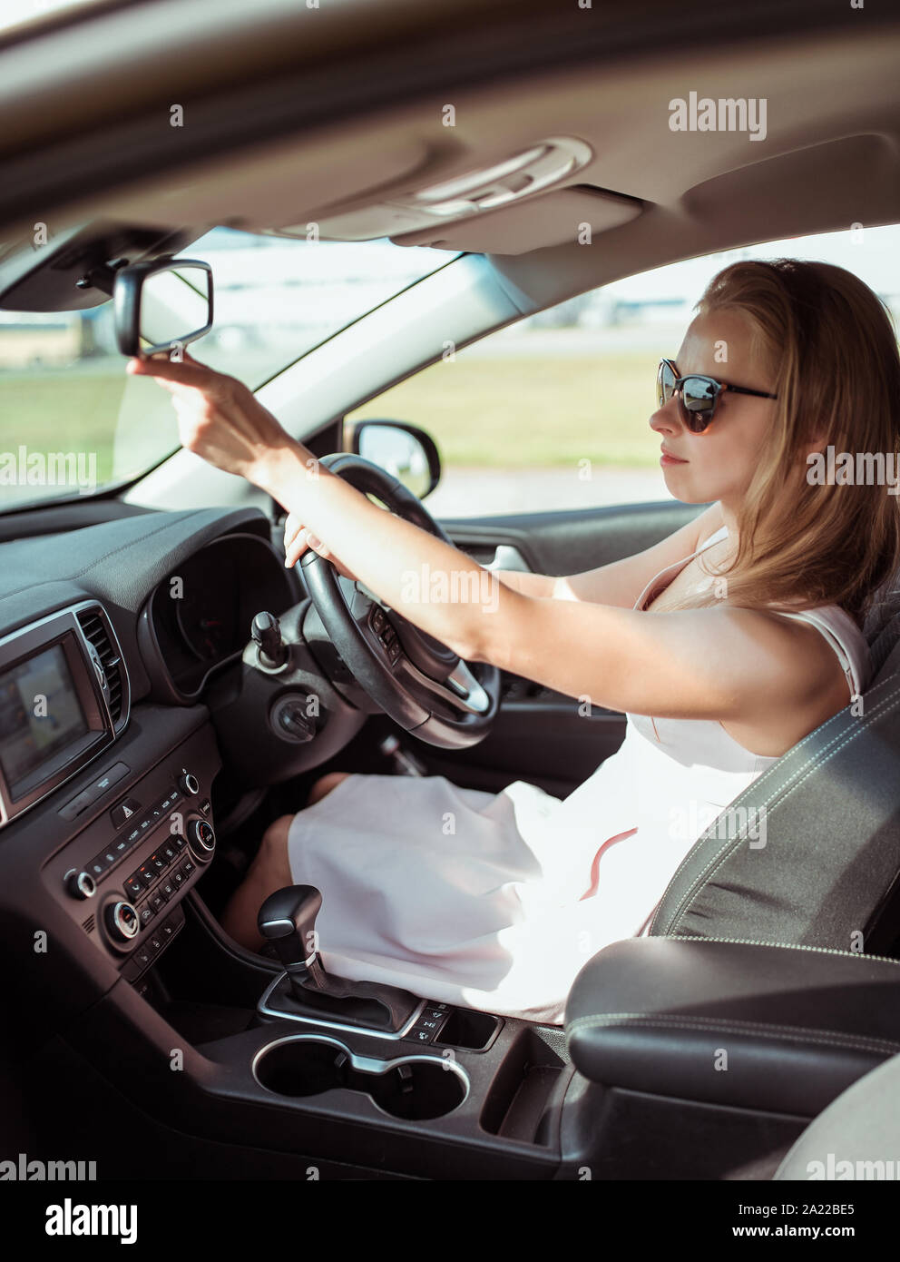 girl car, looks rearview mirror, parks parking lot of shopping center