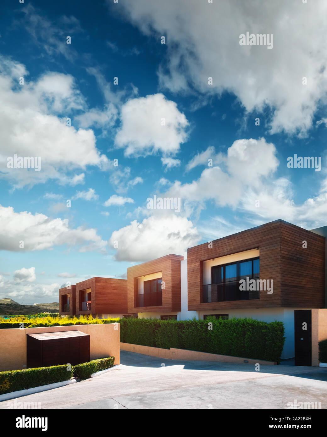 Modern houses with green plant wall on blue sky background. Actual eco architecture Stock Photo