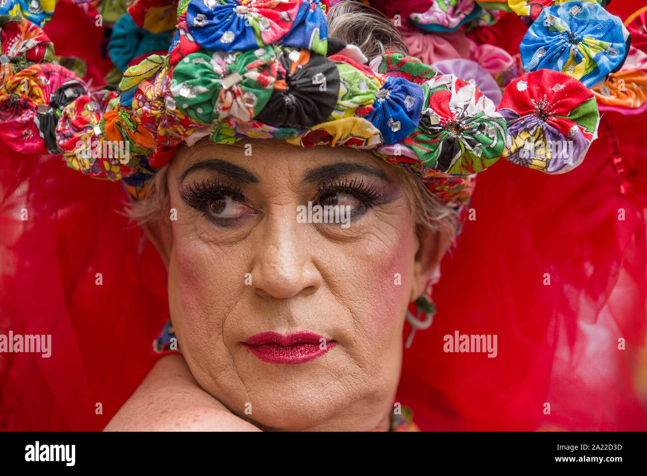 Brazilian Drag Queen wearing red dress and colorful garland Stock Photo
