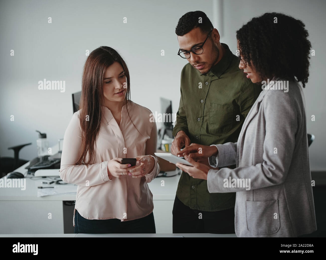Group of multiethnic young concentrated businesspeople using digital tablet at workplace Stock Photo